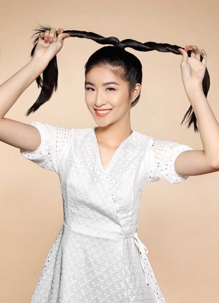 ผู้หญิงเอเชียผมยาวสีดำ กำลังไขว้ผมให้เป็นเกลียว