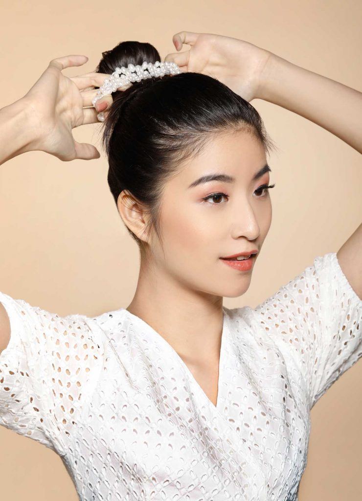 ผู้หญิงเอเชียผมยาวสีดำ กำลังเกล้าผมบัน