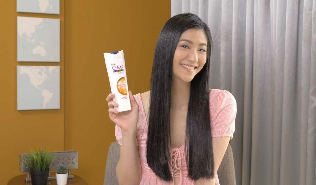 ผู้หญิงเอเชียไว้ผมยาว สีดำ ถือขวดแชมพูเคลียร์