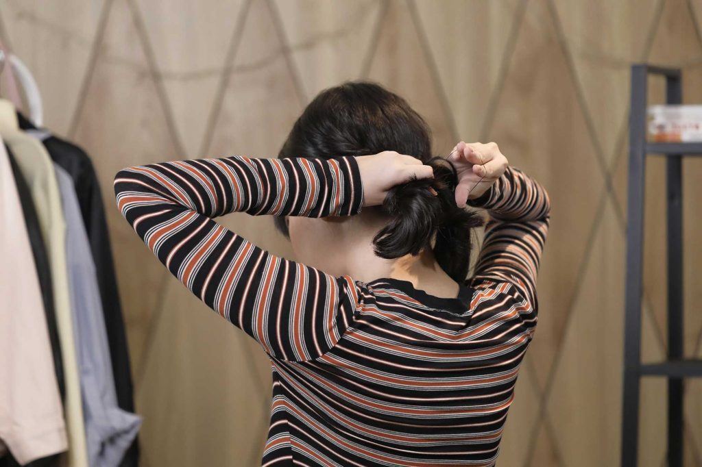 ผู้หญิงเอเชียผมประบ่าสีดำ กำลังมัดผม