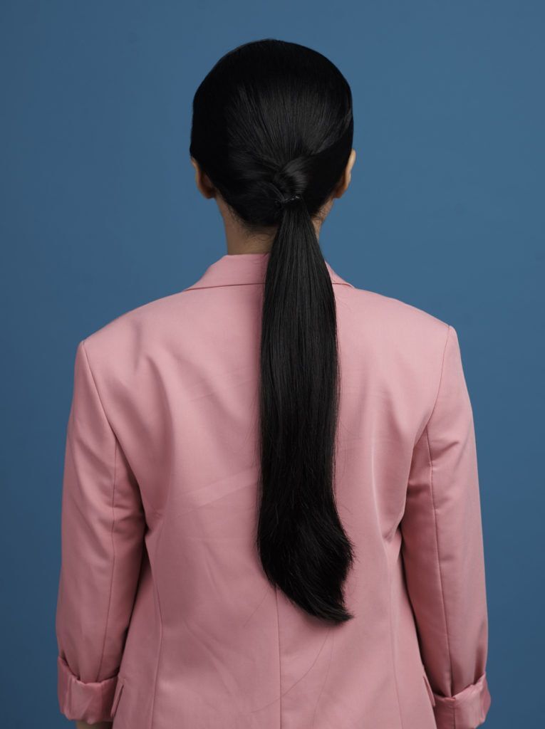 ผู้หญิงผมยาวสีดำ มัดผมหางม้า สวมสูทสีชมพู