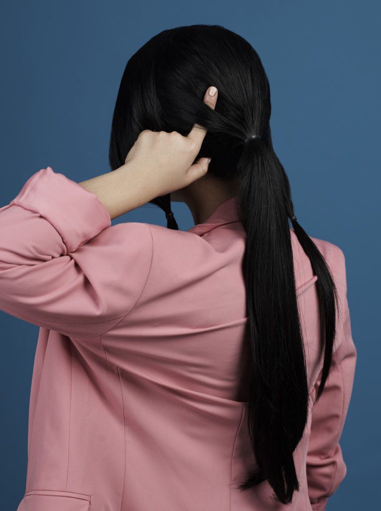 ผู้หญิงผมยาวสีดำ มัดผมหางม้า สวมสูทสีชมพู