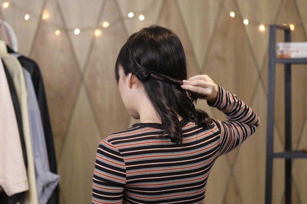 ผู้หญิงเอเชียผมประบ่าสีดำ กำลังบิดผม