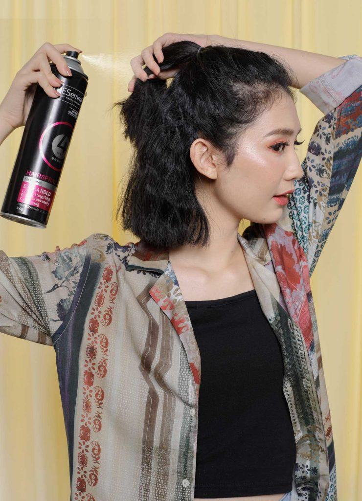 ผู้หญิงเอเชียผมสั้นหยักศกสีดำ กำลังฉีดสเปรย์