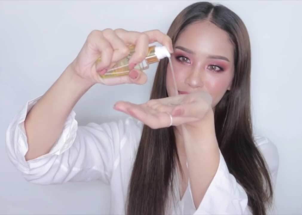 ผู้หญิงไทย ผมยาว เททำเซรั่มบำรุงผม ลงบนฝ่ามือ