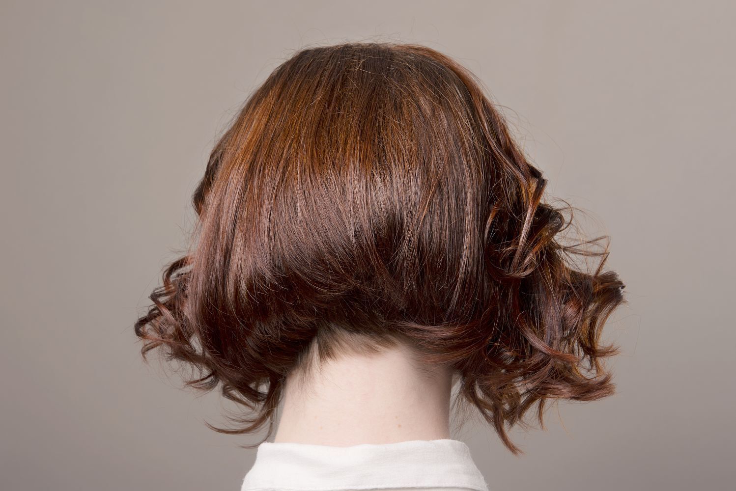 ผู้หญิงหันหลัง ไว้ผมสั้น สีน้ำตาลแดง โชว์ทรงผมบ๊อบสัั้นที่ดัดปลายแค่เพียงส่วนหน้า