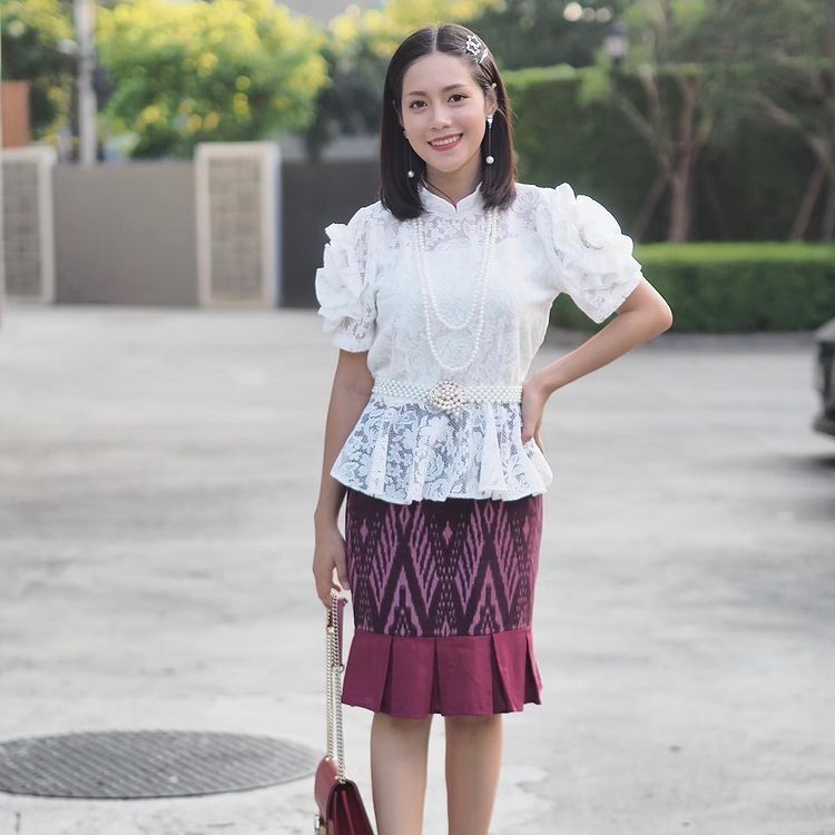 สาวไทย ใส่เสื้อลูกไม้ ทำผมบ๊อบยาว แสกกลางติดกิ๊บหนึ่งข้าง