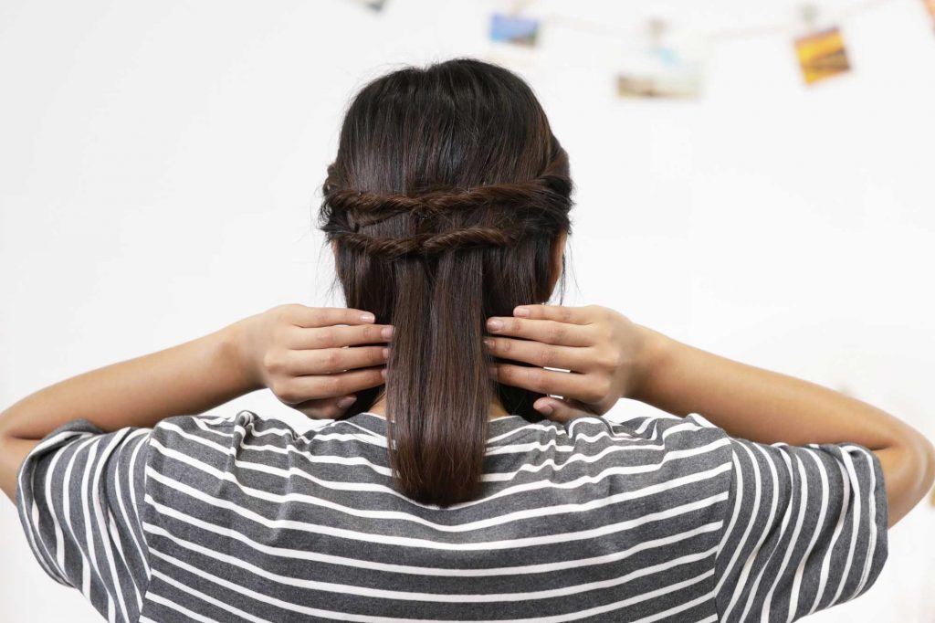 ผู้หญิงเอเชียผมยาวประบ่าสีดำ กำลังถักเปีย