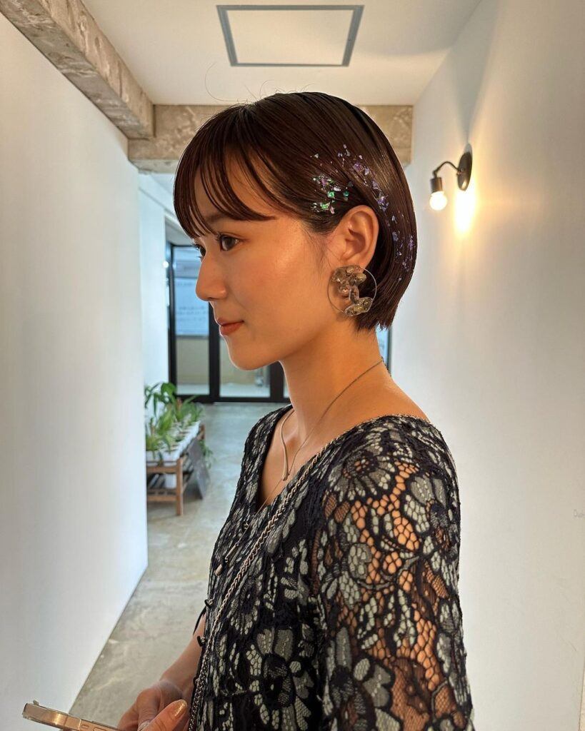 ผู้หญิงเอเชีย ผิวขาว ผมบ๊อบสั้น เหน็บหู ติดกลิตเตอร์ด้านข้าง 