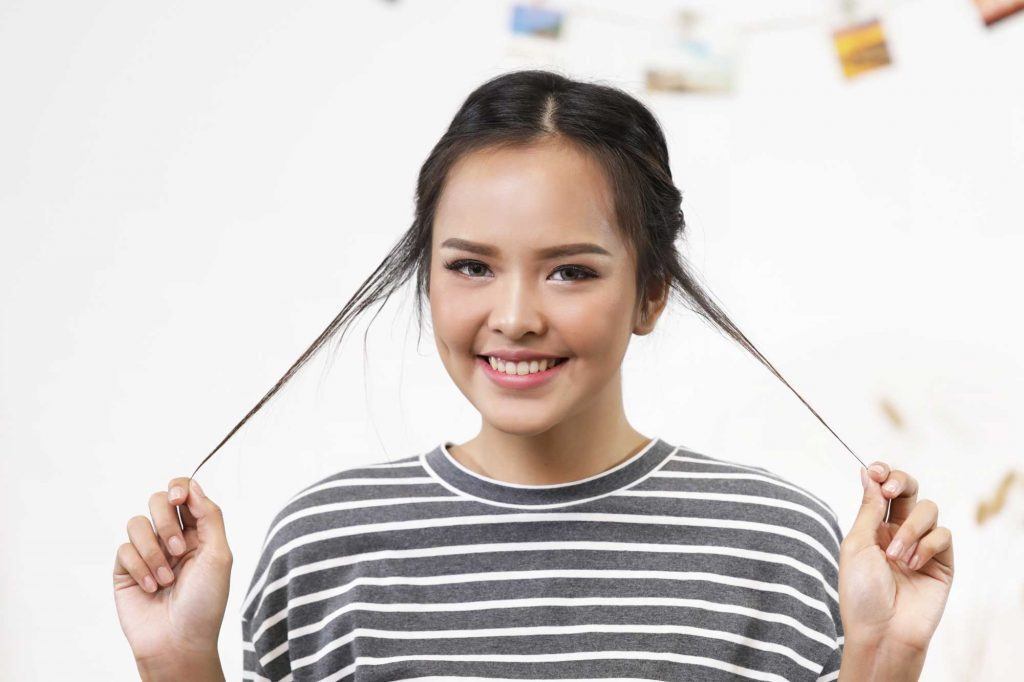 ผู้หญิงเอเชียผมยาวประบ่าสีดำ กำลังดึงปอยผม