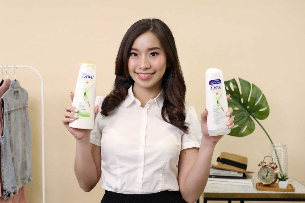 ผู้หญิงเอเชียผมยาวสีดำ กำลังถือขวดแชมพูและครีมนวดผม