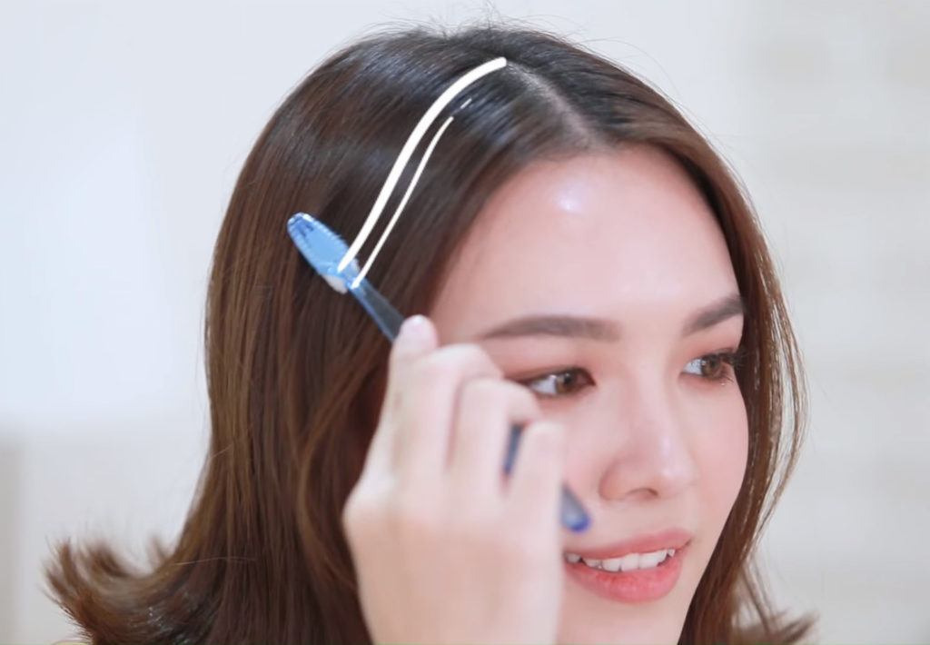 หญิงสาว ใช้แปรงสีฟัน  ลูบบนผม เก็บลูกผมด้านหน้า