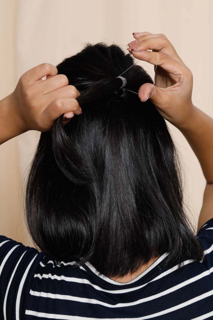 ผู้หญิงเอเชียหน้ากลมผิวคล้ำผมสั้น กำลังมัดผม