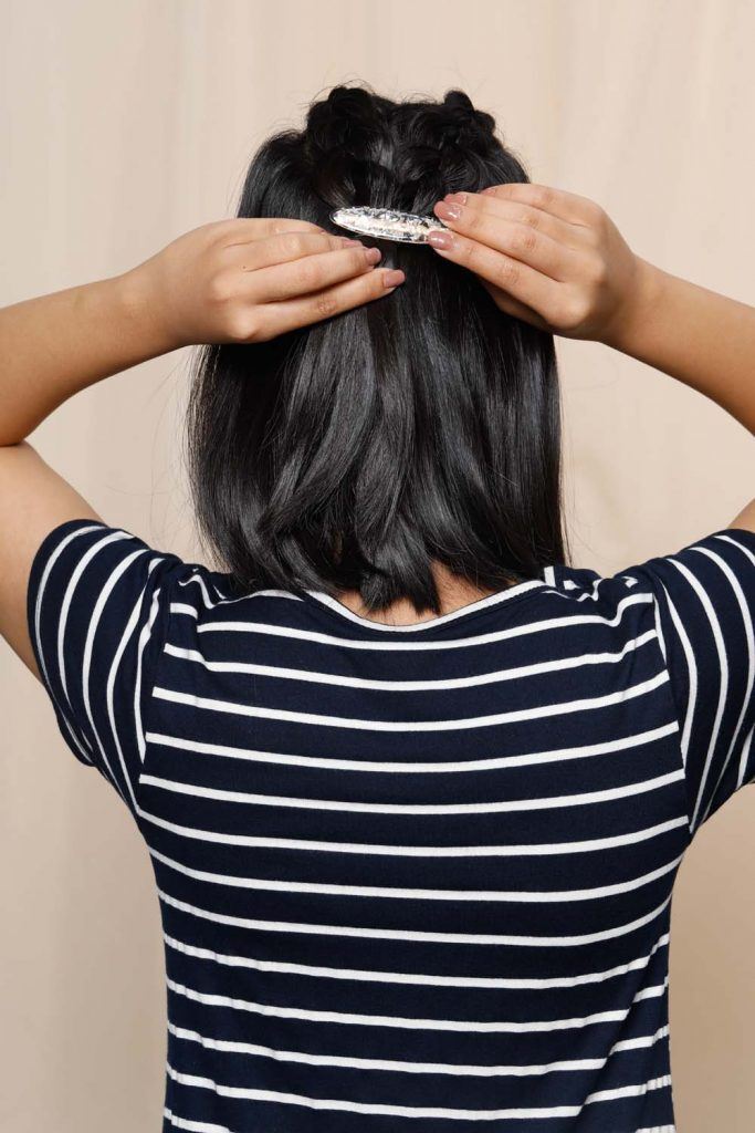 ผู้หญิงเอเชียหน้ากลมผิวคล้ำผมสั้น กำลังใช้กิ๊บหนีบผม