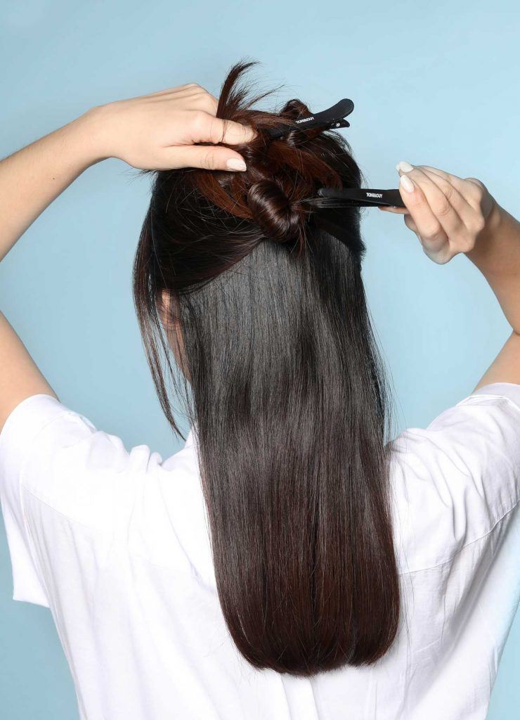 ผู้หญิงเอเชียผมยาว กำลังแบ่งผม แล้วหนีบด้วยกิ๊บปากเป็ด