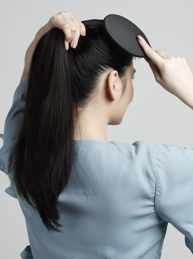 ผู้หญิงผมยาวสีดำ ถักเปียหางม้า สวมเสื้อสีฟ้า