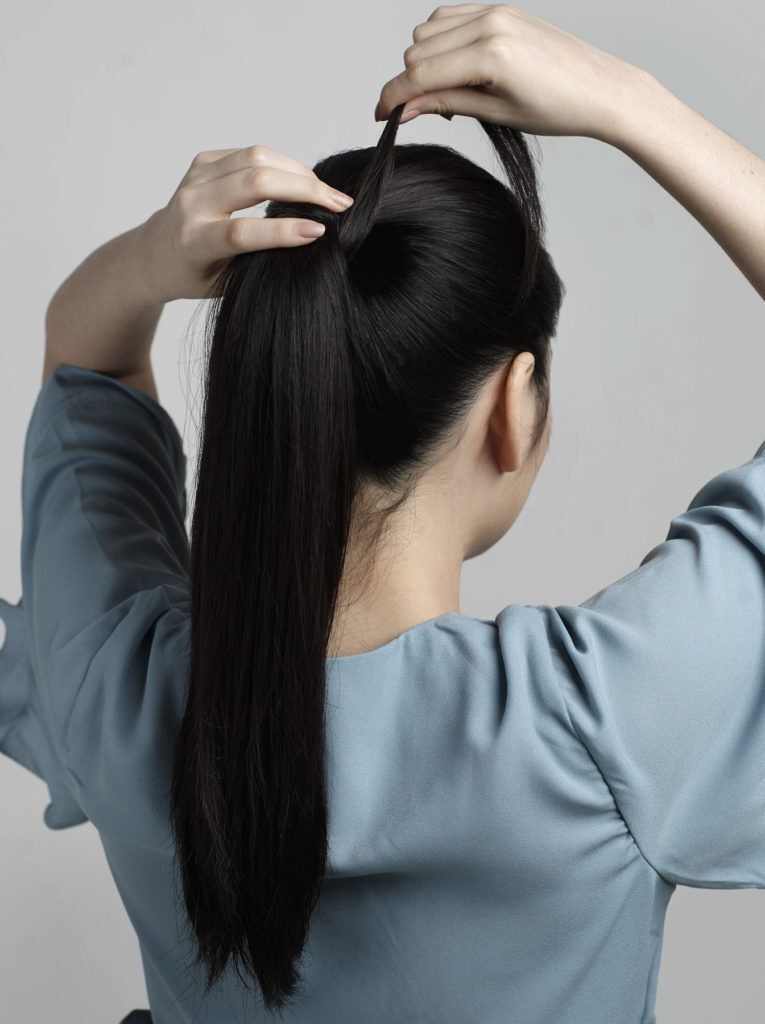 ผู้หญิงผมยาวสีดำ ถักเปียหางม้า สวมเสื้อสีฟ้า