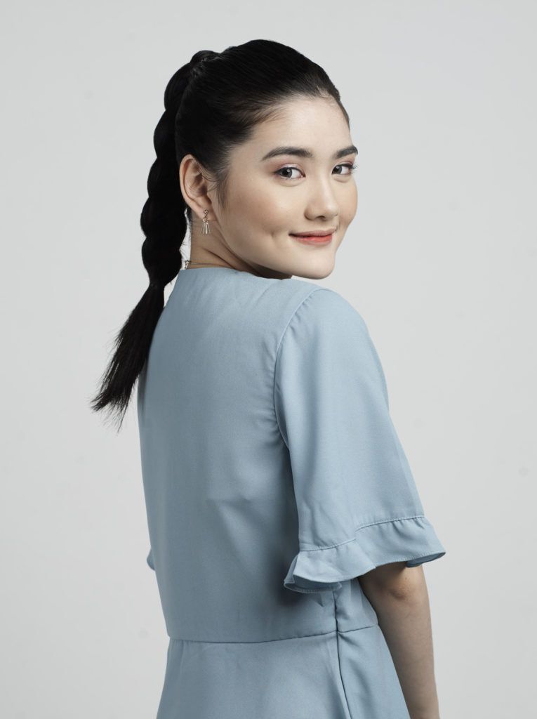 ผู้หญิงผมยาวสีดำ ถักเปียหางม้า สวมเสื้อสีฟ้า