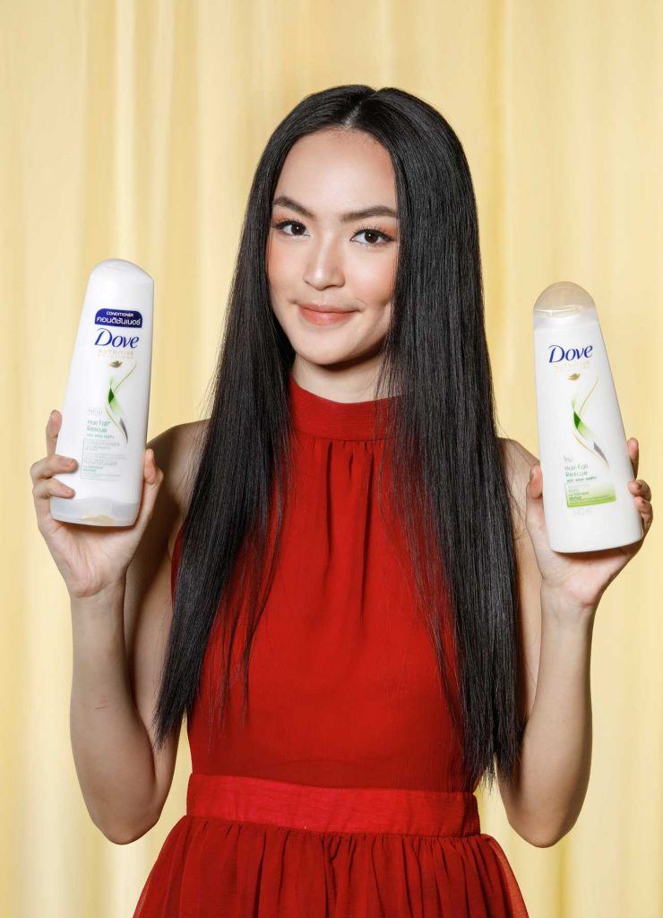 ผู้หญิงเอเชียผมยาวสีดำ กำลังถือขวดแชมพูและครีมนวดผม