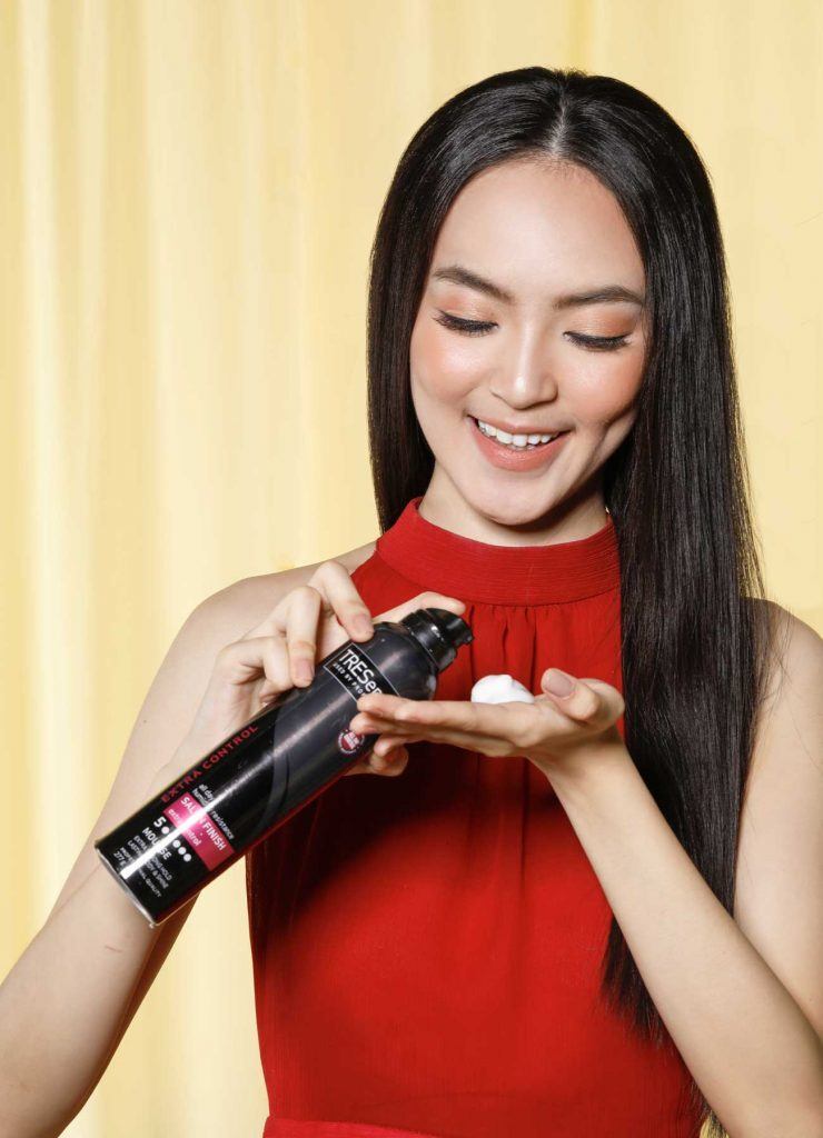 ผู้หญิงเอเชียผมยาวสีดำ กำลังบีบมูสลงบนฝ่ามือ