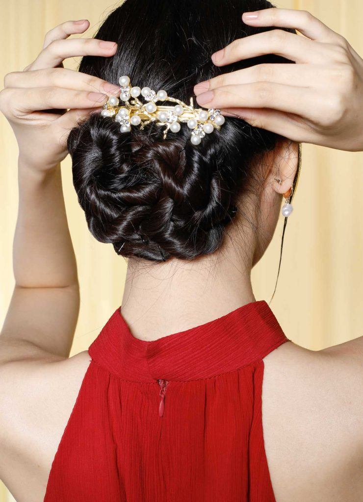 ผู้หญิงเอเชียผมยาวสีดำ กำลังติดเครื่องประดับลงบนผมเกล้า