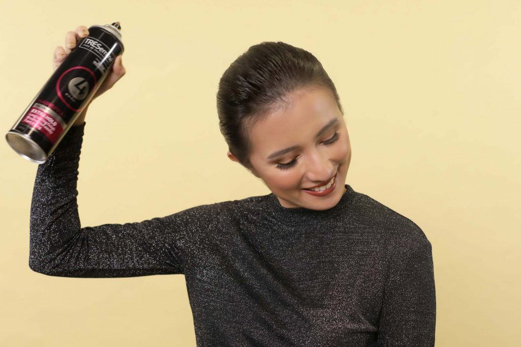 ผู้หญิงเอเชีย ผมสั้นสีดำ กำลังฉีดสเปรย์บนผม 