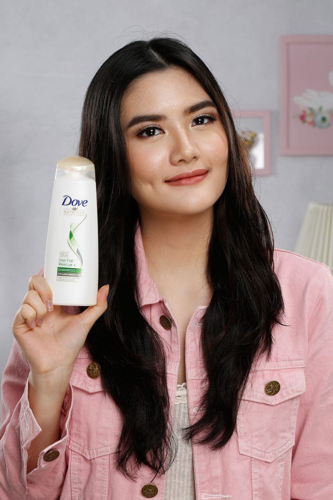 ผู้หญิงเอเชียผมยาวกำลังถือขวดแชมพูโดฟ