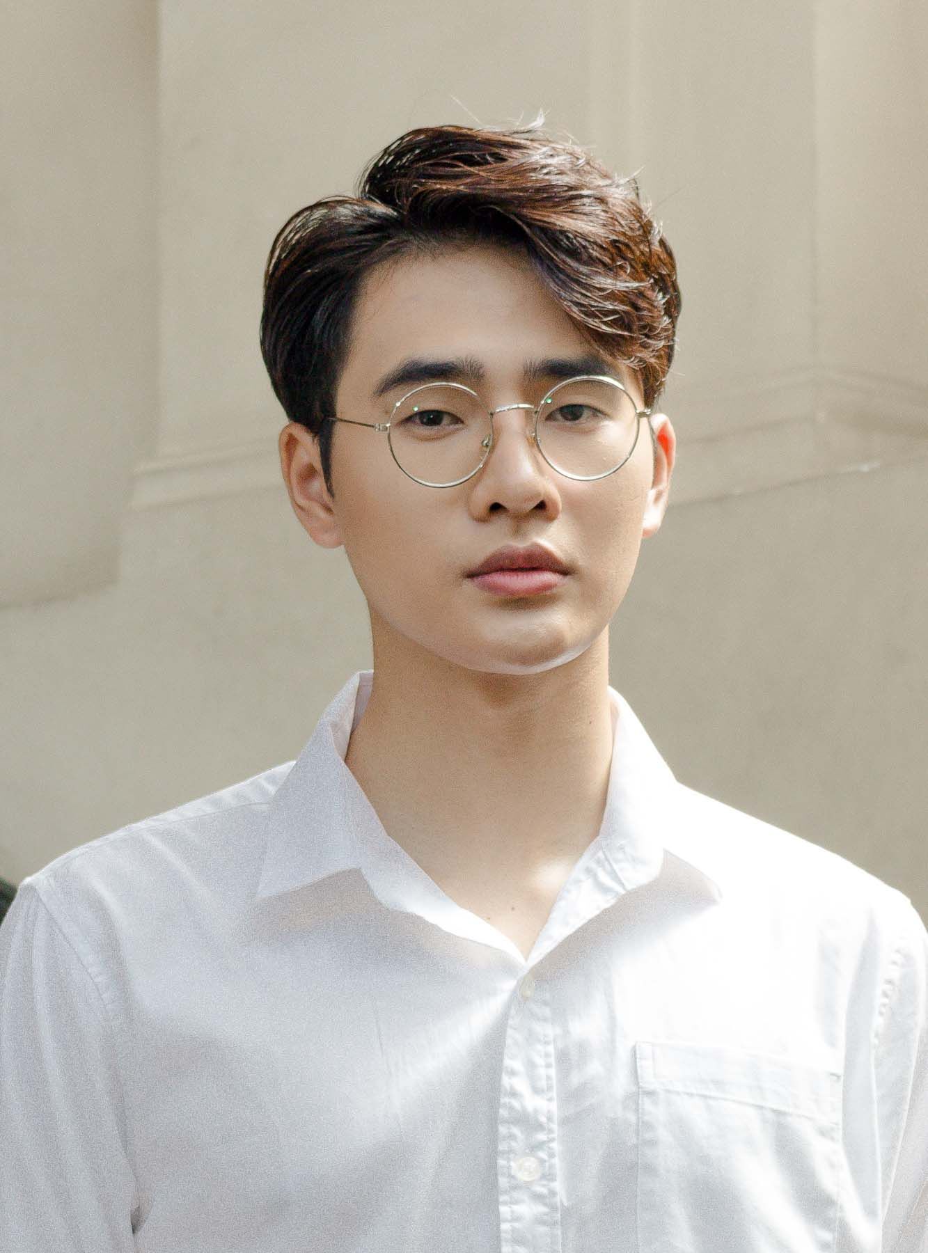 ผู้ชายไทยตัดผมสั้น ใส่เสื้อเชิ้ตสีขาว ใส่แว่นสายตา