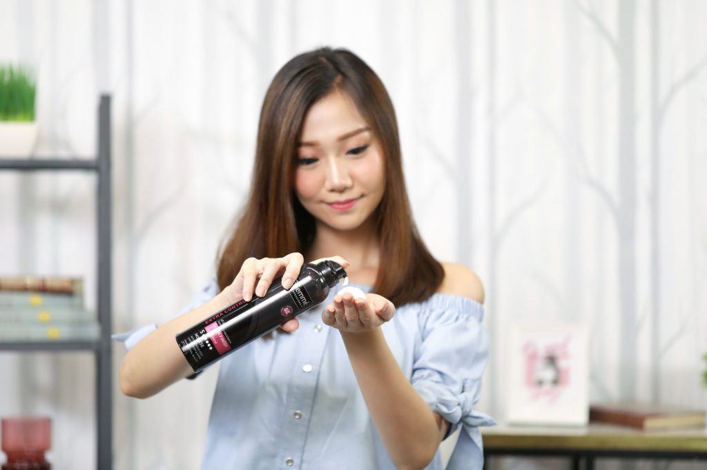 ผู้หญิงเอเชียผมยาวประบ่าสีดำ กำลังบีบมูสลงบนฝ่ามือ