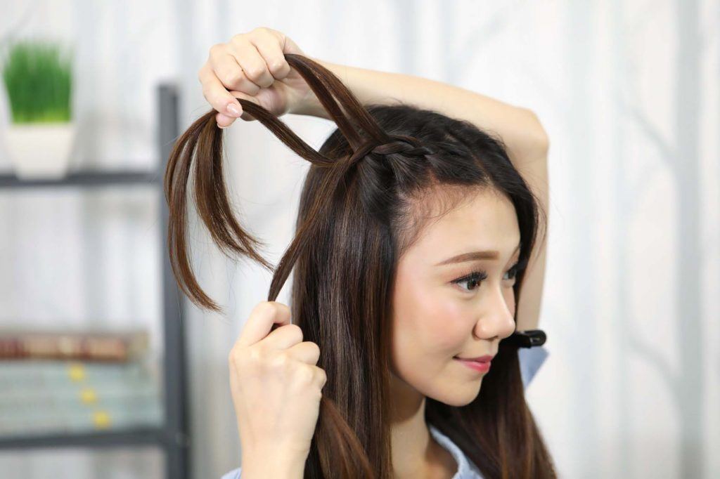 ผู้หญิงเอเชียผมยาวประบ่าสีดำ กำลังถักเปีย