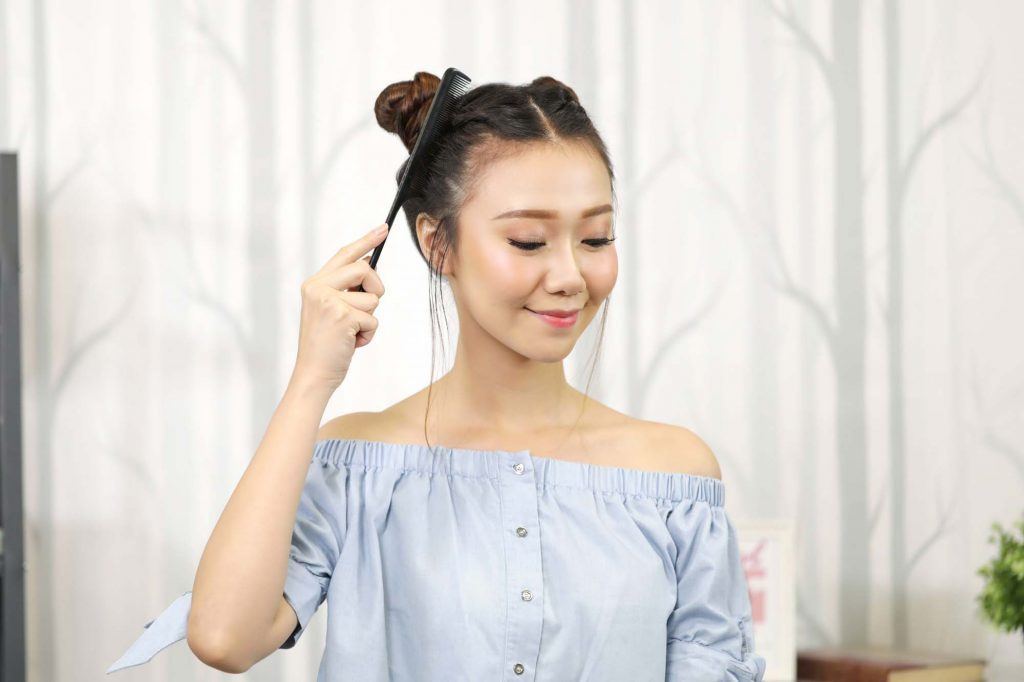 ผู้หญิงเอเชียผมยาวประบ่าสีดำ กำลังใช้หวีหางหวีผมให้เรียบ