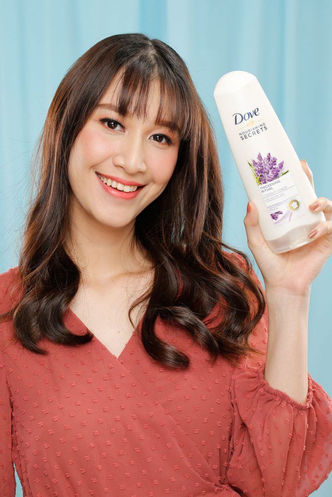 ผู้หญิงเอเชียผมยาวสีดำ กำลังถือขวดแชมพู โดฟ