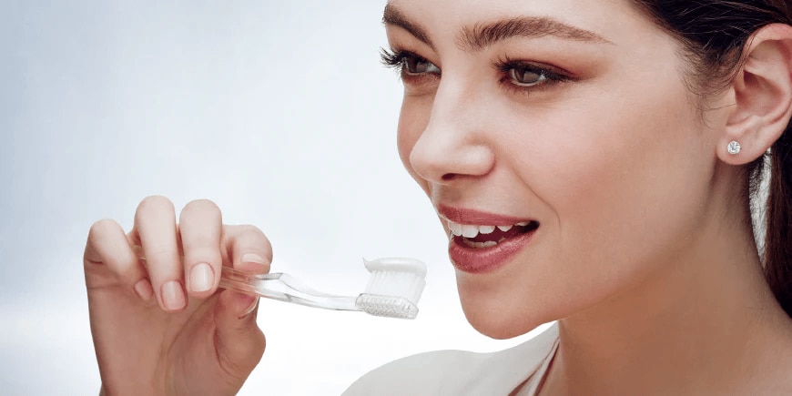 caries prevención mujer cepillar dientes con regenerate dentífrico