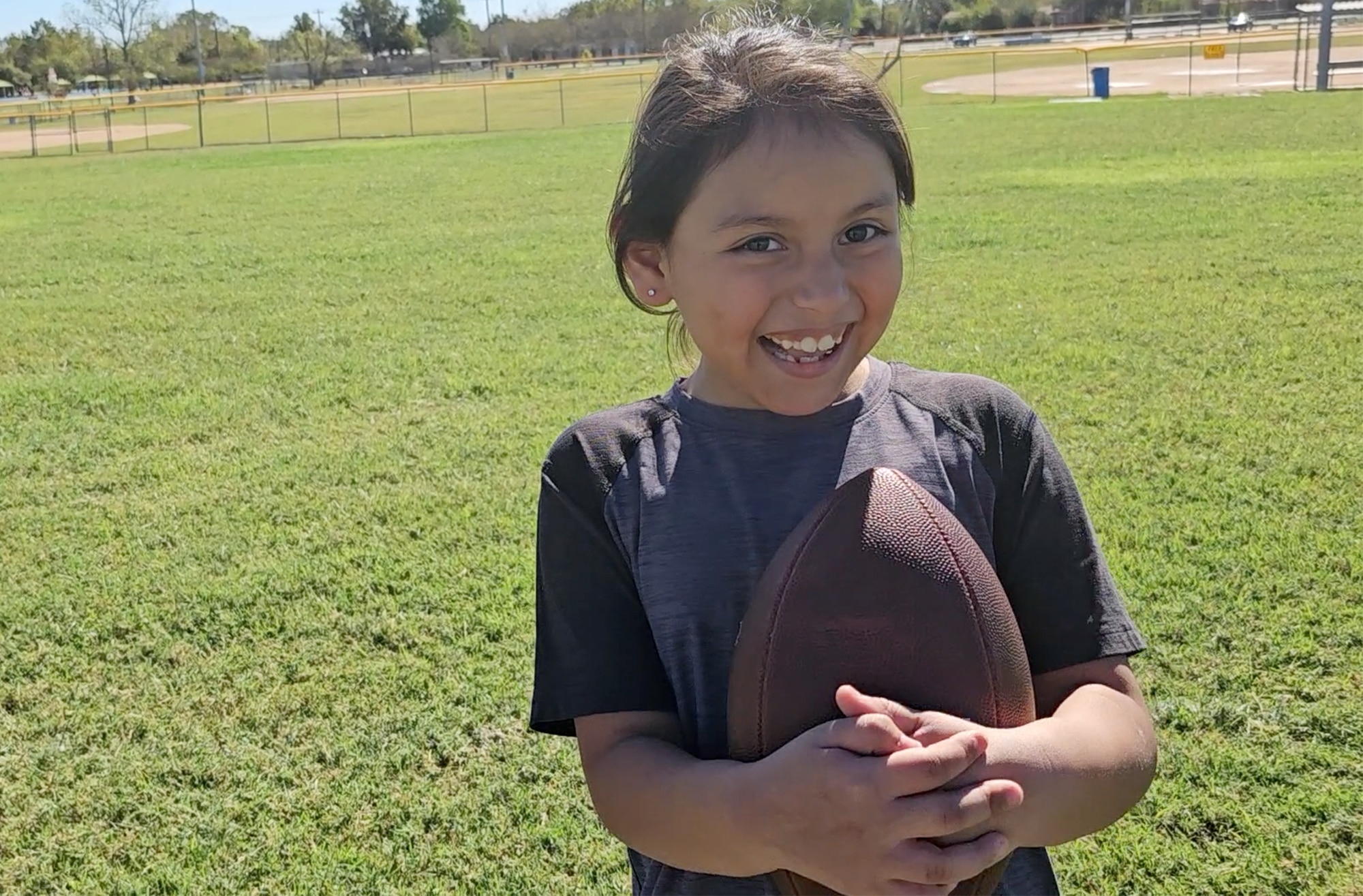 Validy smiling holding a football on a field