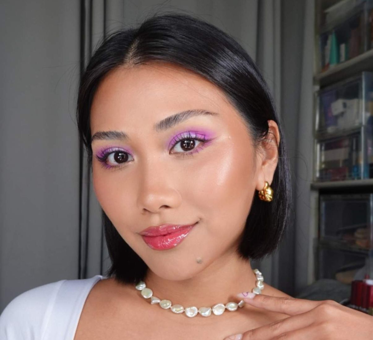A Filipina beauty creator in purple eyeshadow and glossy red lips.