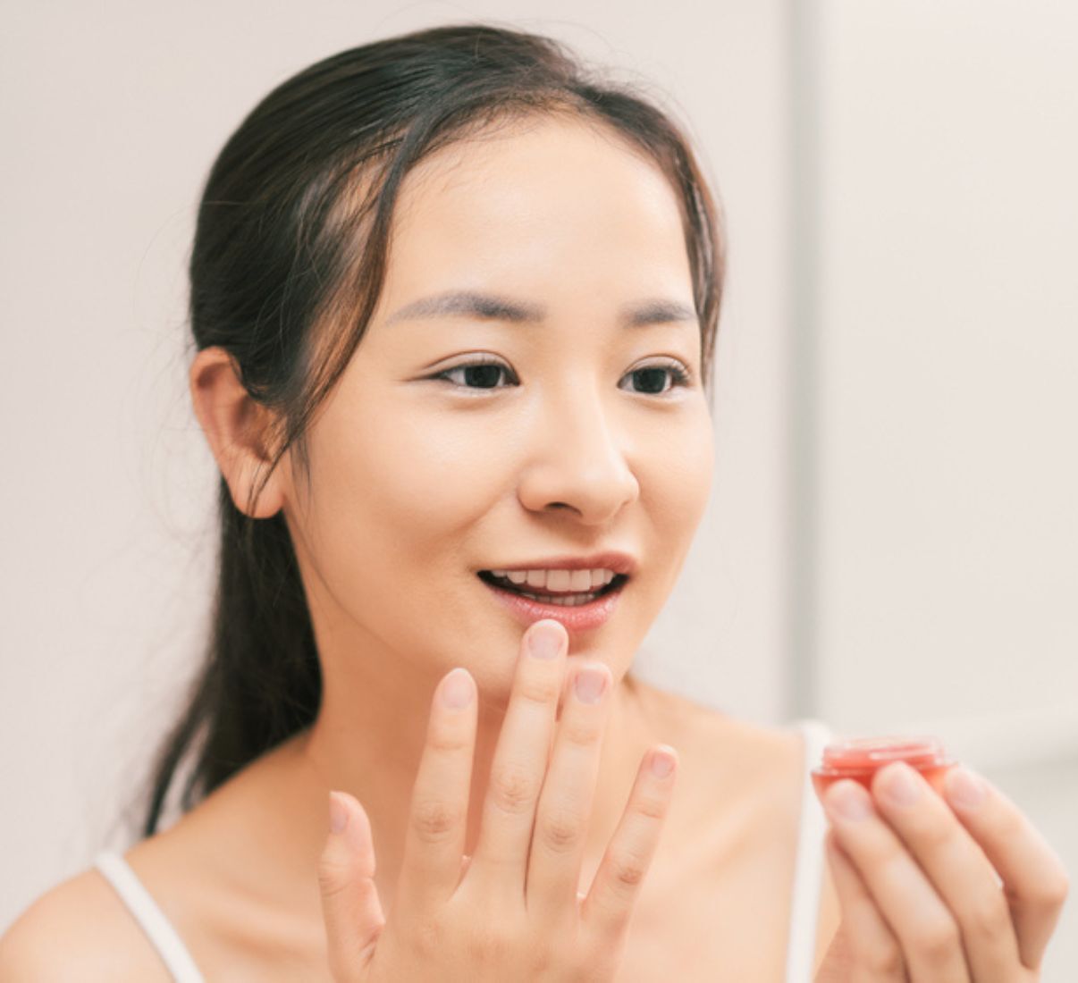Woman applying lip balm to her lips.