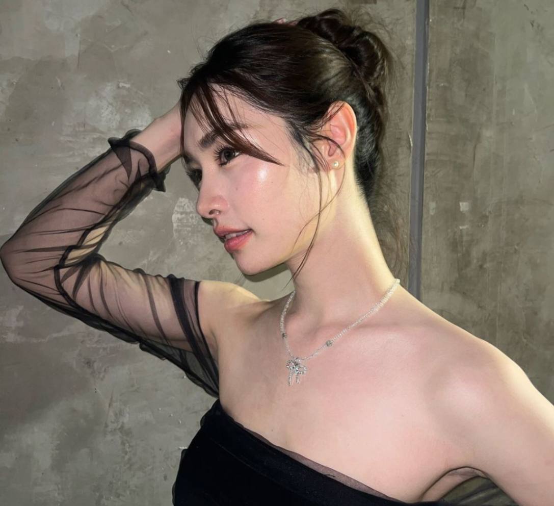 Woman with hair bun wearing a stylish black top.