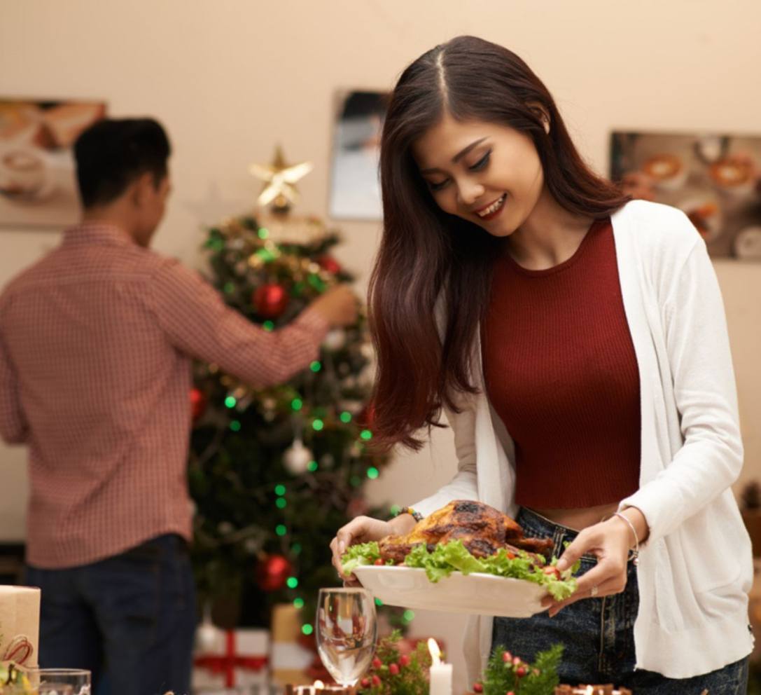 Asian woman holding roast chicken for Christmas.