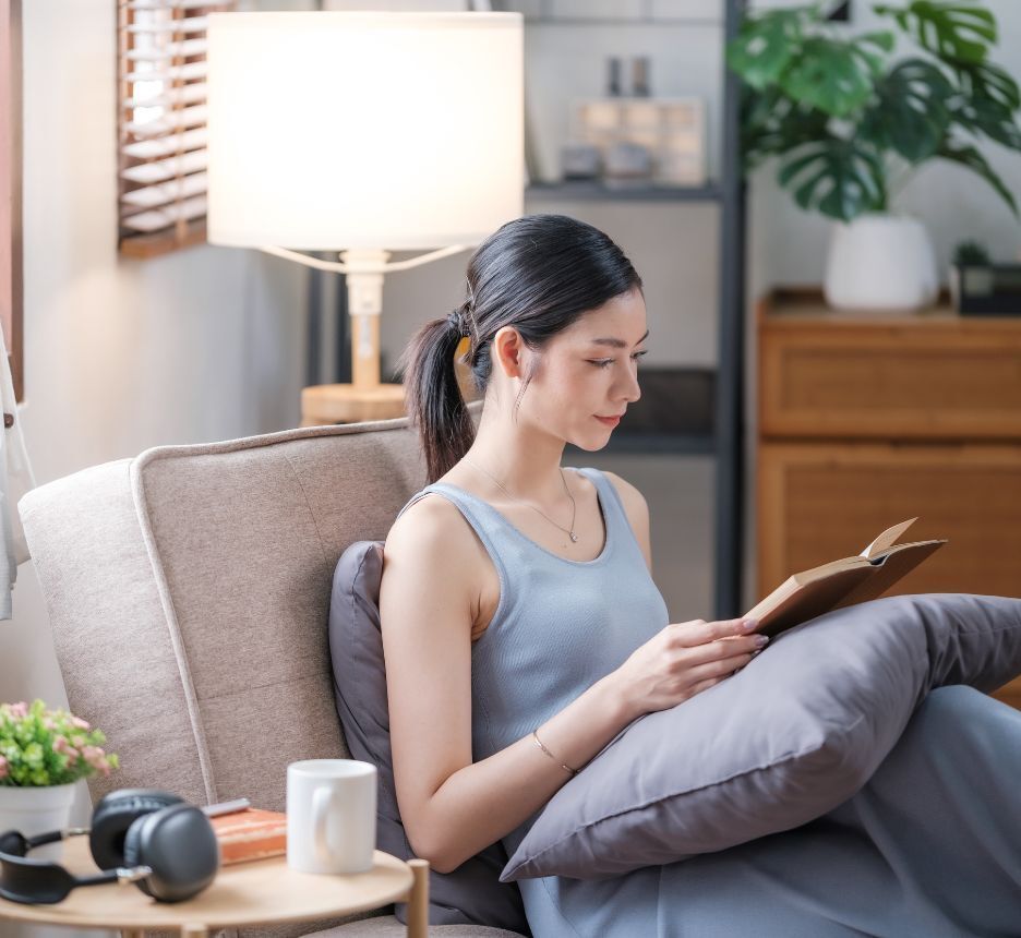 Woman reading a book while sitting on a sofa at home.