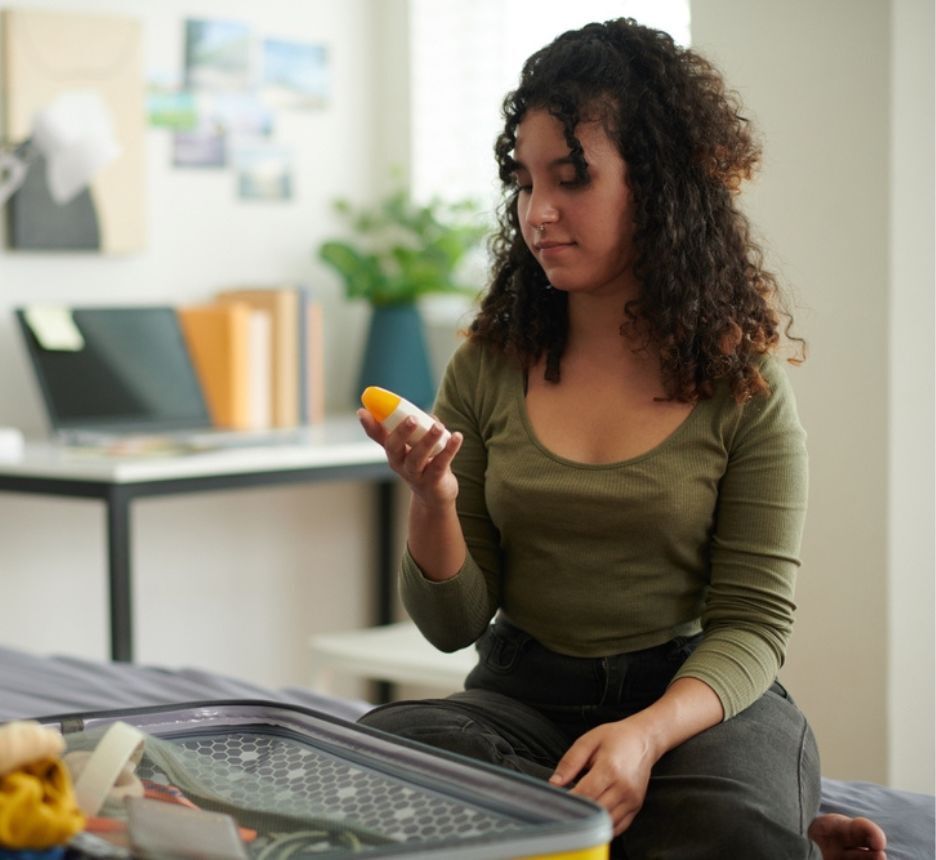 Woman packs skincare in her luggage.