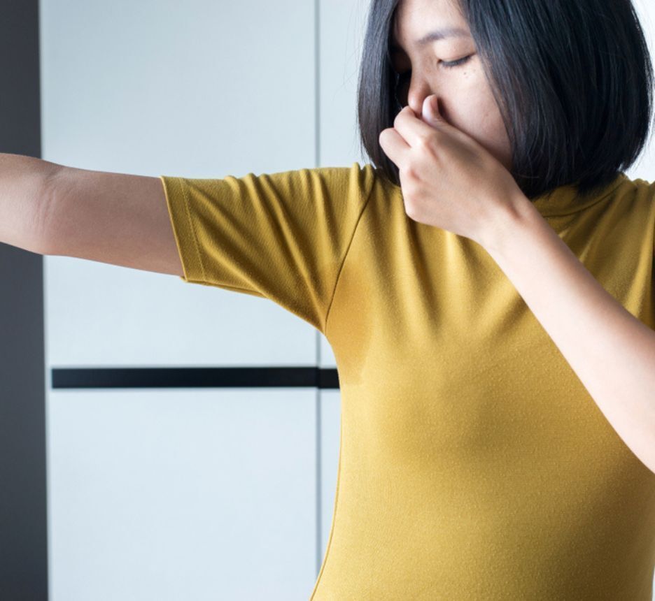 Woman raising her arm while covering her nose with her finger.