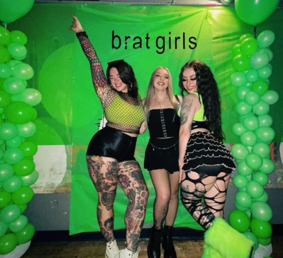 Three women posing in front of a green backdrop.