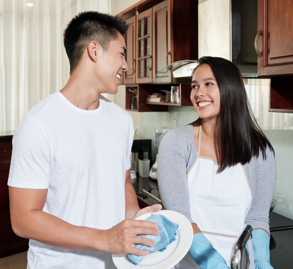 Asian boyfriend and girlfriend washing dishes at home.