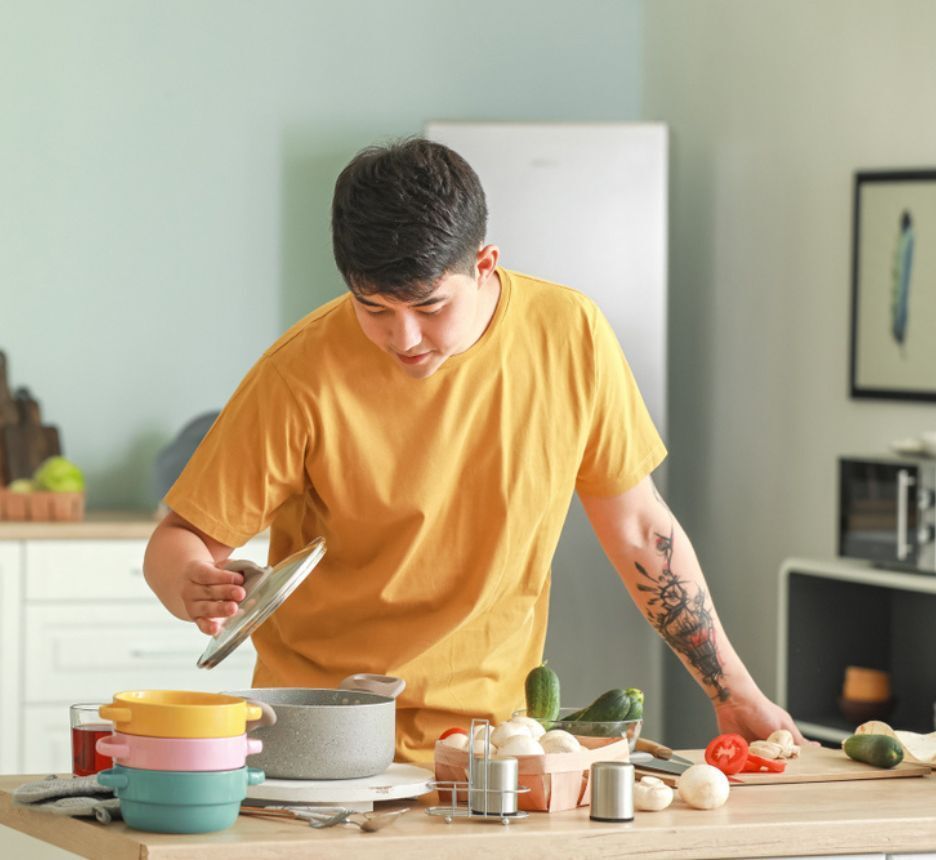 Man with tattoos cooking in his kitchen.