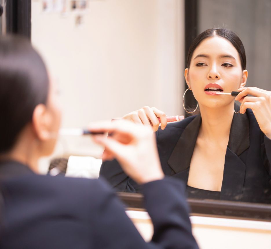 Professional-looking woman applying lipstick.