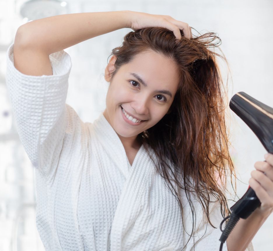 Woman blow-drying her hair in the bathroom.