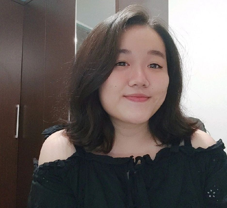 Woman in black off-shoulder top smiling.