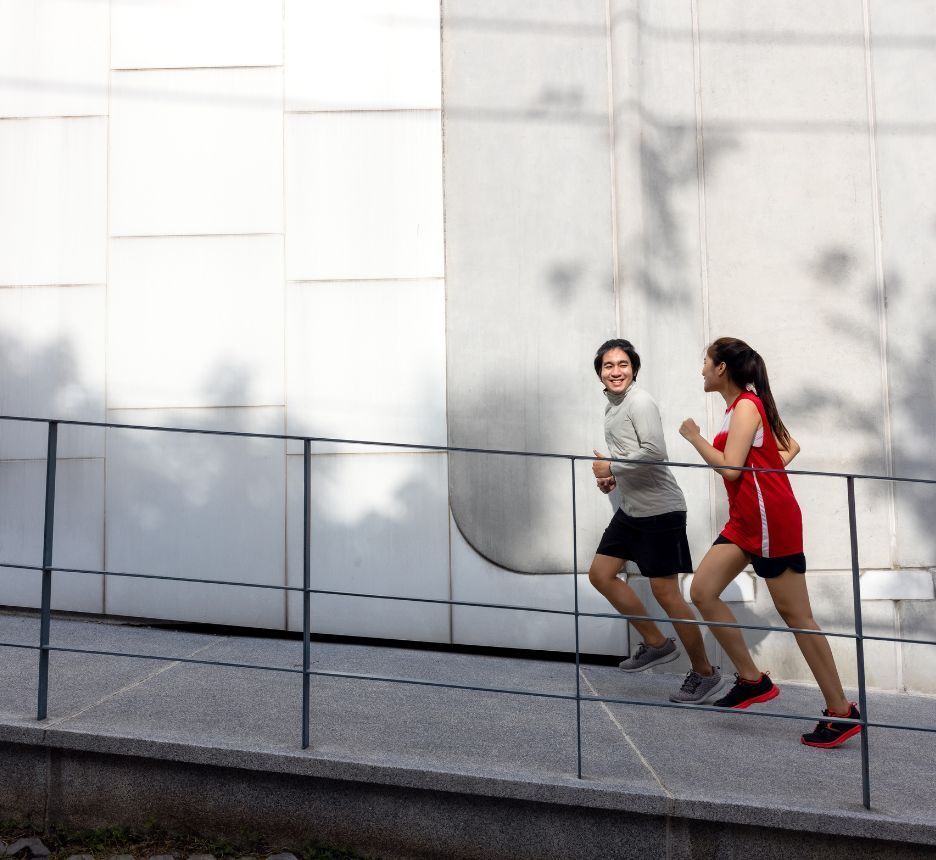 Man and woman run upwards an inclined area near building.