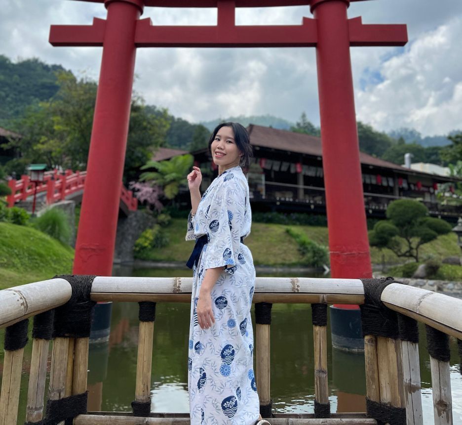 Woman in kimono posing in front of a torii gate.