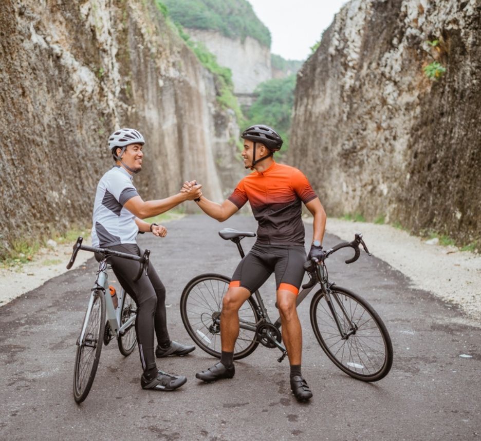 Two men shaking hands after riding bikes together.